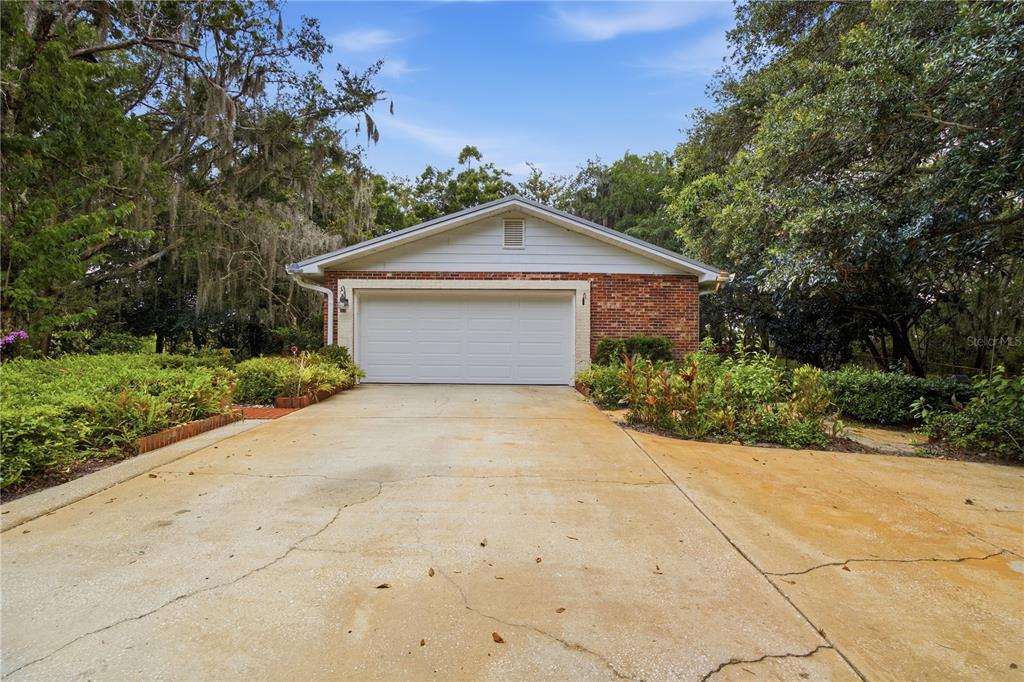 A detached brick garage with a white door sits at the end of a concrete driveway — 2271 KEYSTONE ROAD, TARPON SPRINGS, FL