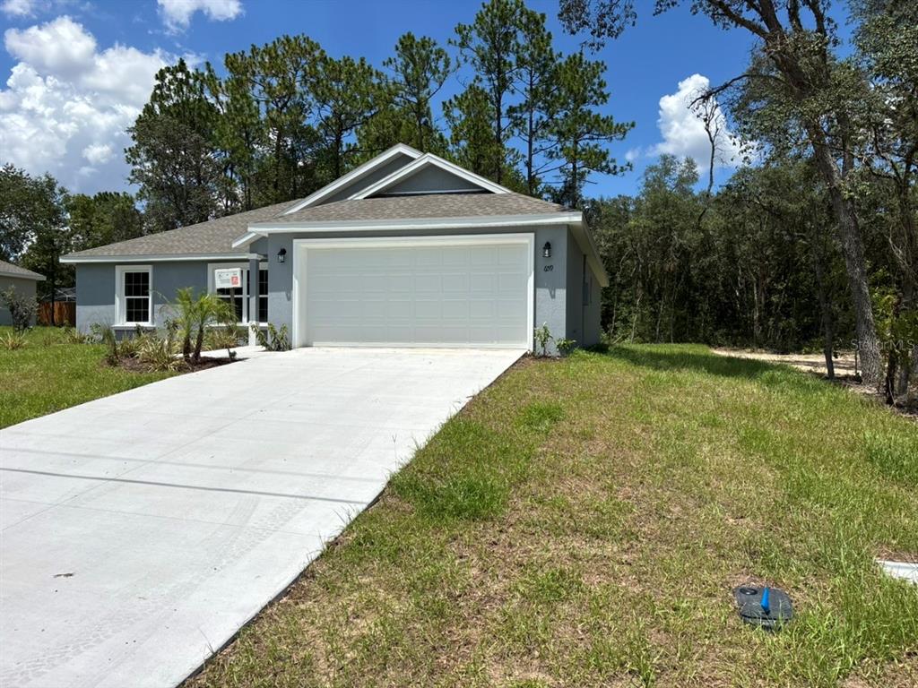 A single-story house with a gray exterior, a two-car garage, and a concrete driveway — 659 W BANCROFT DRIVE, DUNNELLON, FL