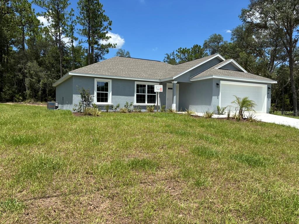 A single-story gray house with a two-car garage and a grassy front yard — 659 W BANCROFT DRIVE, DUNNELLON, FL