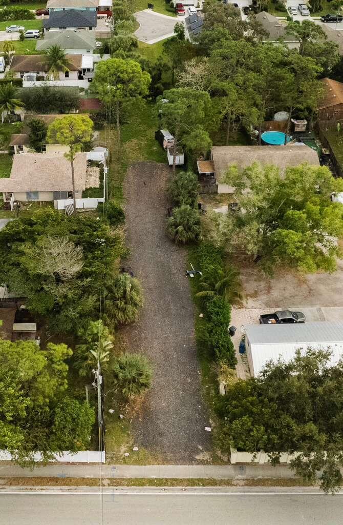 An aerial view shows a gravel driveway extending from a road between two residential properties — 3630 S Haverhill Road, FL 33463, FL