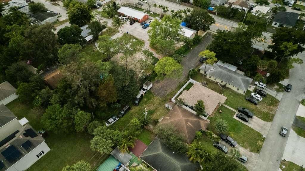An aerial view shows residential houses, dense trees, and parked cars along a paved street — 3630 S Haverhill Road, FL 33463, FL