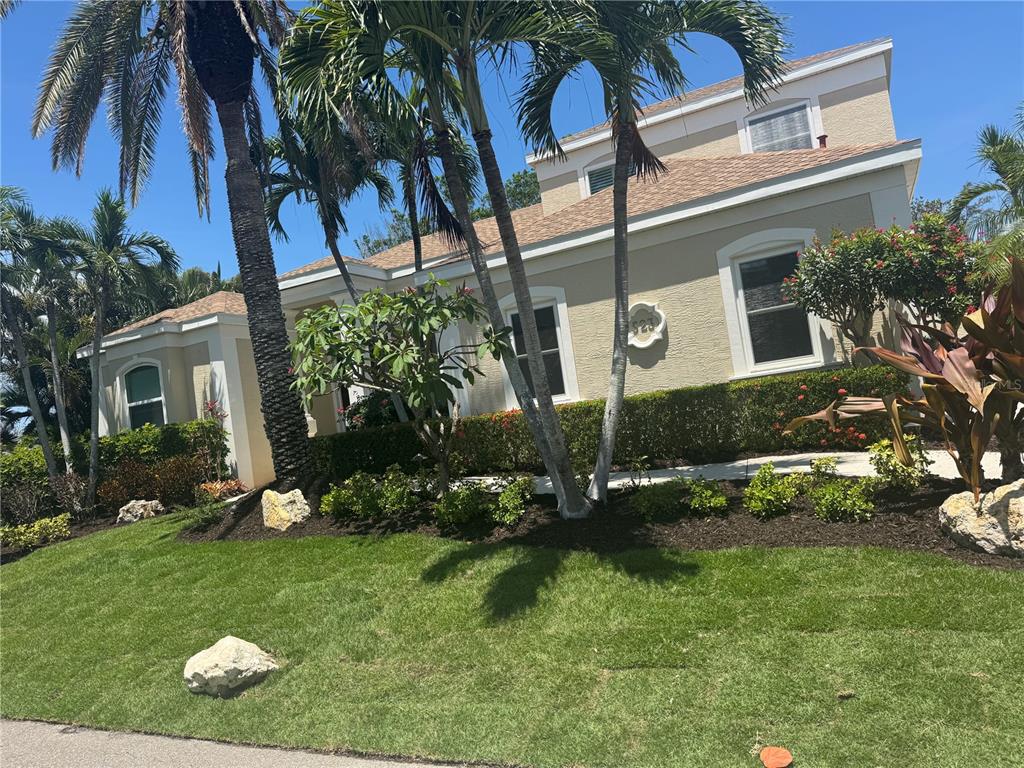 A two-story tan house with a palm-lined front yard and manicured landscaping — 523 JUAN ANASCO DRIVE, LONGBOAT KEY, FL