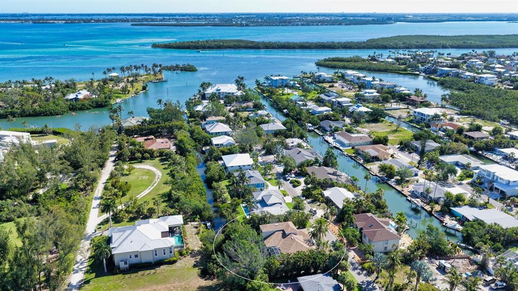 An aerial view shows a residential neighborhood with houses along canals leading to open water — 523 JUAN ANASCO DRIVE, LONGBOAT KEY, FL