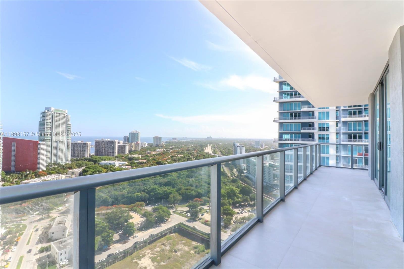 A high-rise balcony with a glass railing overlooks a city skyline and green space — 1300 S miami # 2706, Miami FL 33130, MIAMI, FL