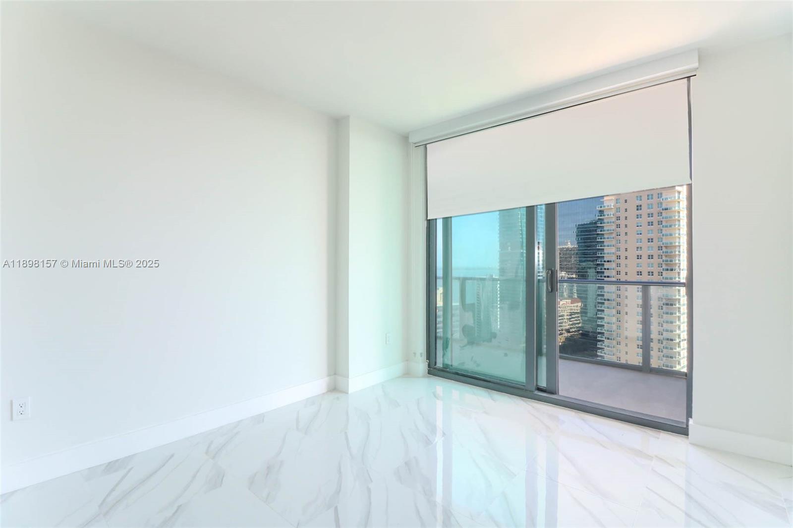 An empty room features white walls, marble-patterned tile flooring, and a sliding glass balcony door — 1300 S miami # 2706, Miami FL 33130, MIAMI, FL