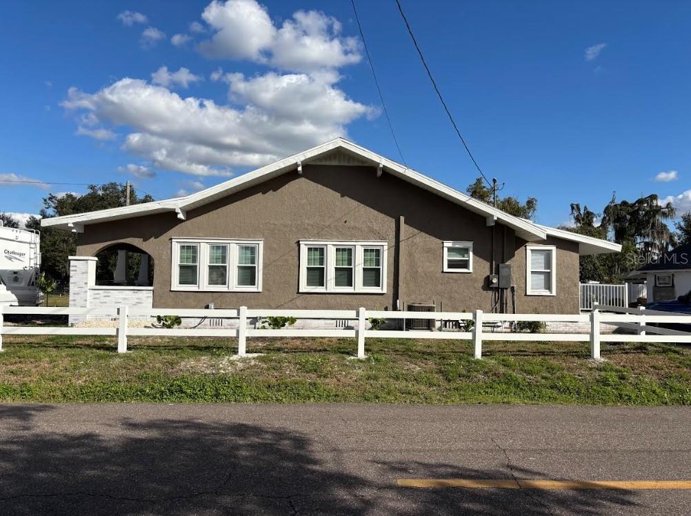 A single-story house with a brown stucco exterior, white trim, and a white picket fence — 2403 BURNS STREET, LAKELAND, FL