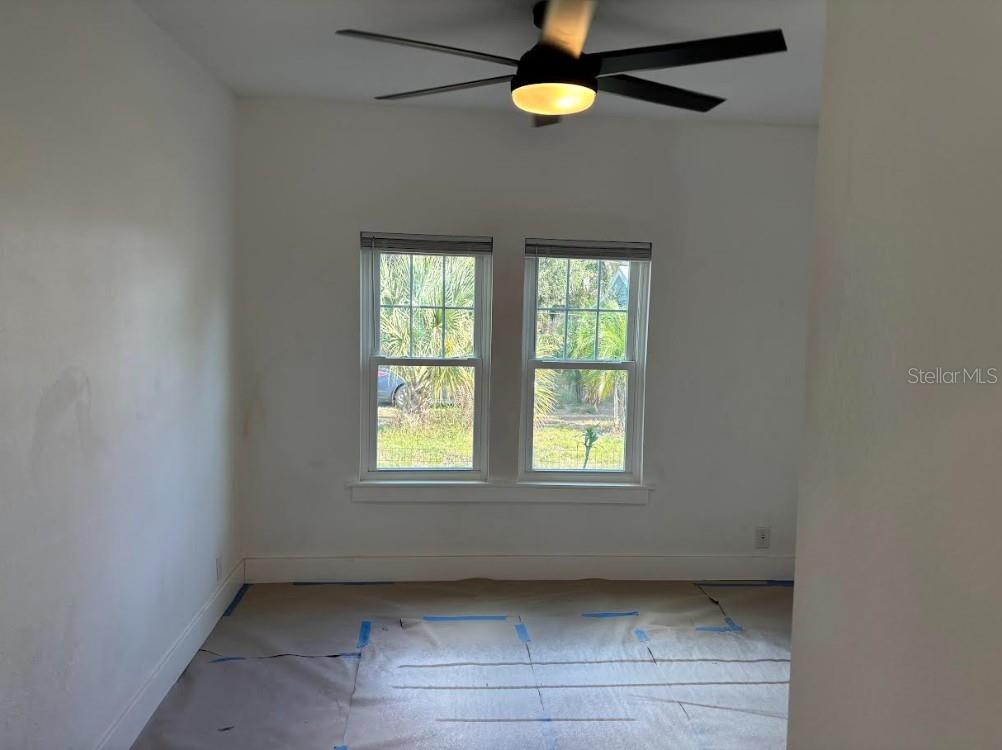 An empty room with white walls, two windows, and a ceiling fan over floor protection — 2403 BURNS STREET, LAKELAND, FL
