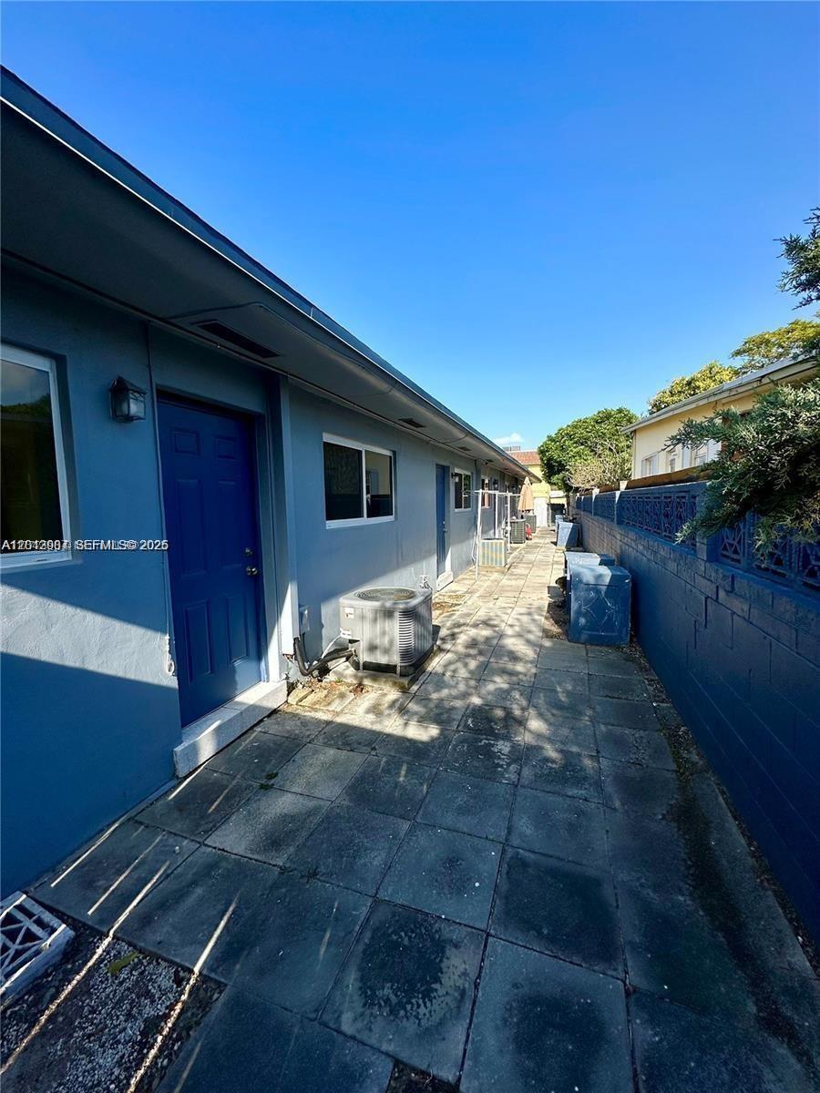 A narrow paved walkway runs alongside a blue building with a blue door and AC unit — 1821 N 17th Ct # 26, Hollywood FL 33020, HOLLYWOOD, FL