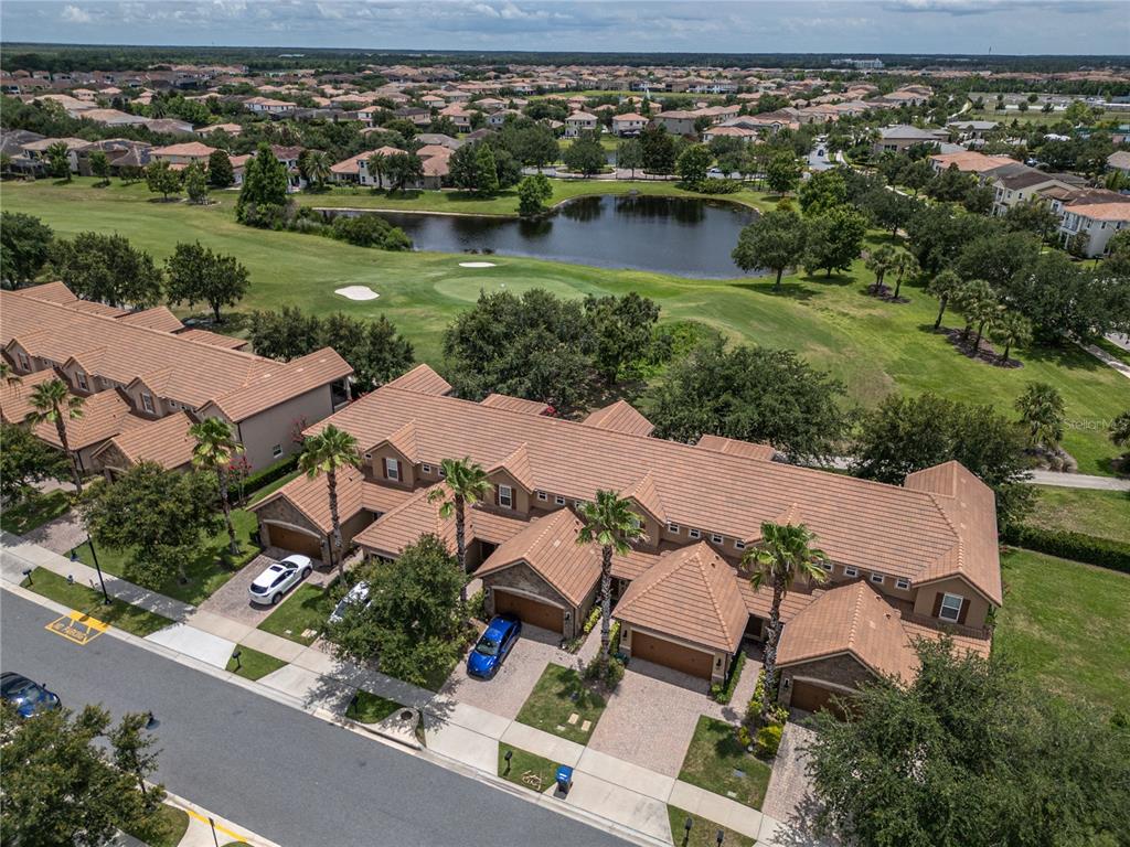An aerial view shows a multi-unit townhouse complex with tile roofs overlooking a golf course — 10751 BELFRY CIRCLE, ORLANDO, FL