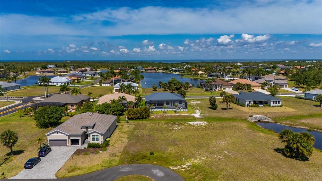 An aerial view shows several suburban houses situated near a lake under a blue sky — 16429 AYSON WAY, PUNTA GORDA, FL
