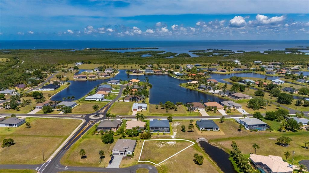 An aerial view shows a vacant residential lot in a coastal neighborhood with nearby houses — 16429 AYSON WAY, PUNTA GORDA, FL