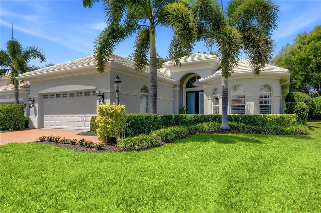 A single-story house with a white exterior, tile roof, and palm trees in the front yard — 12323 THORNHILL COURT, LAKEWOOD RANCH, FL