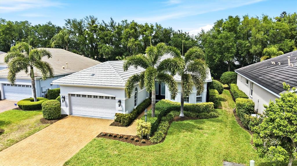 An aerial view shows a single-story house with a light-colored exterior and palm trees — 12323 THORNHILL COURT, LAKEWOOD RANCH, FL