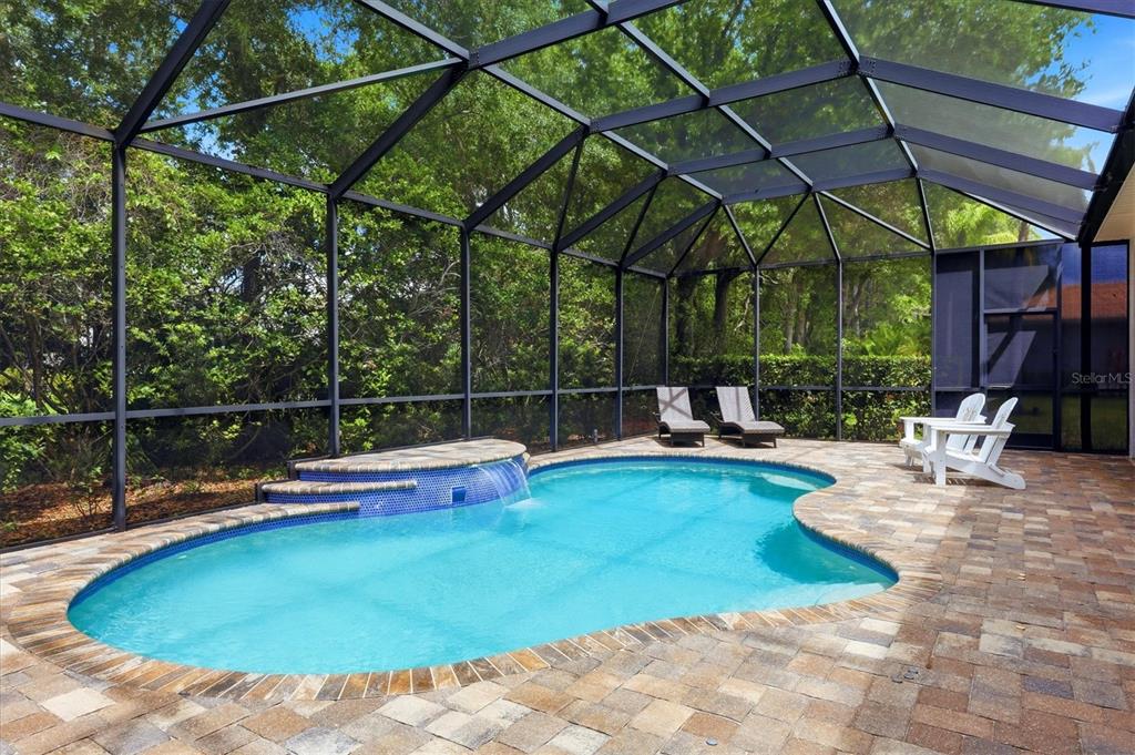 A screened-in patio features a kidney-shaped swimming pool with a waterfall and stone pavers — 12323 THORNHILL COURT, LAKEWOOD RANCH, FL
