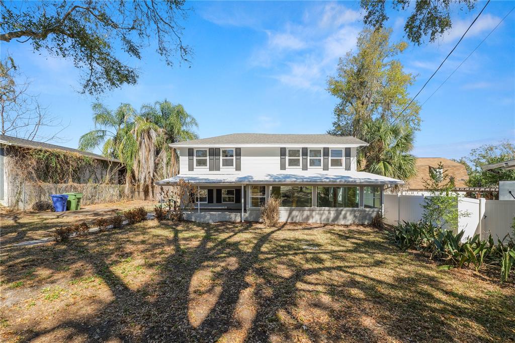 A two-story white house with dark shutters and a large ground-floor sunroom — 961 DREXEL AVENUE NE, WINTER HAVEN, FL