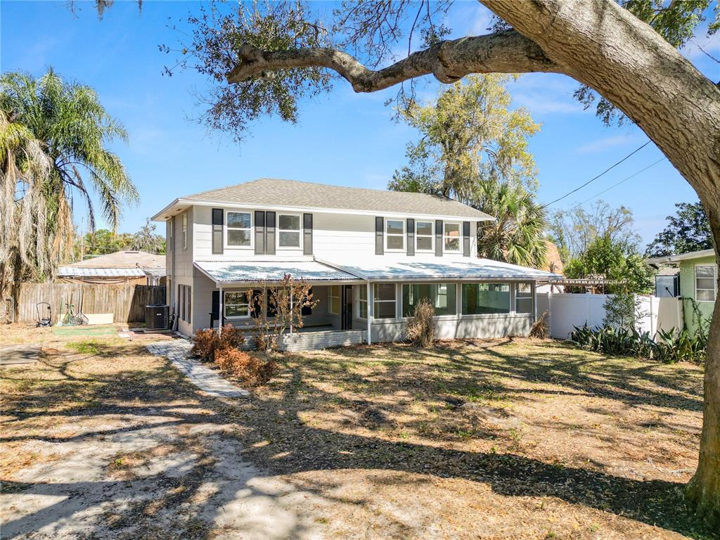 The rear exterior of a two-story house features a covered patio and a large yard — 961 DREXEL AVENUE NE, WINTER HAVEN, FL