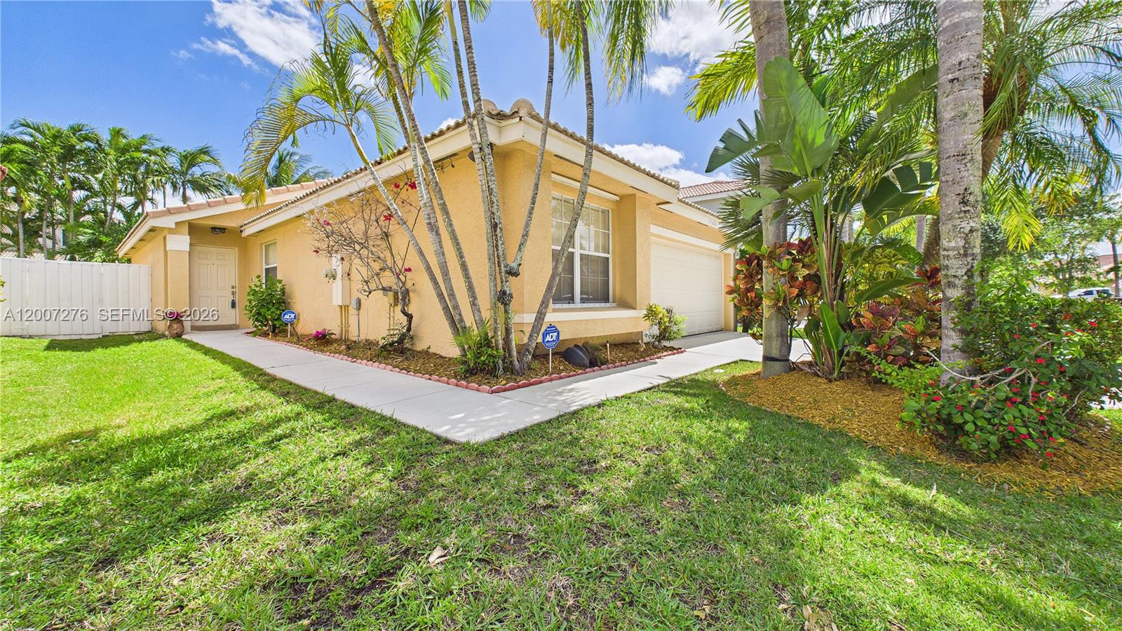 A single-story yellow stucco house features a garage, a front walkway, and tropical landscaping — 17626 SW 20th St, Miramar FL 33029, MIRAMAR, FL