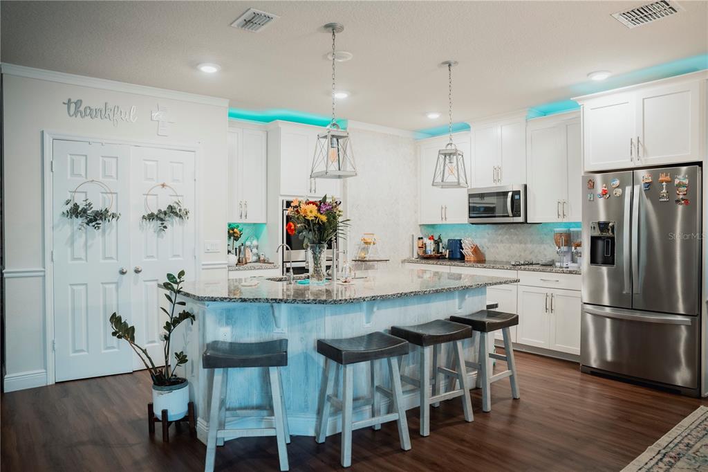A kitchen with white cabinets, granite countertops, a central island with bar seating, and lighting — 2907 SUMMER GREEN TRAIL, KISSIMMEE, FL