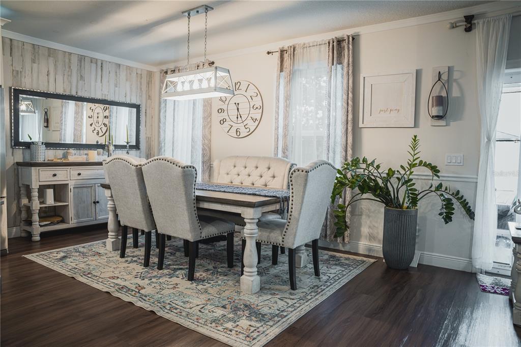 A dining room features a wooden table, upholstered chairs, a bench, and a large wall clock — 2907 SUMMER GREEN TRAIL, KISSIMMEE, FL