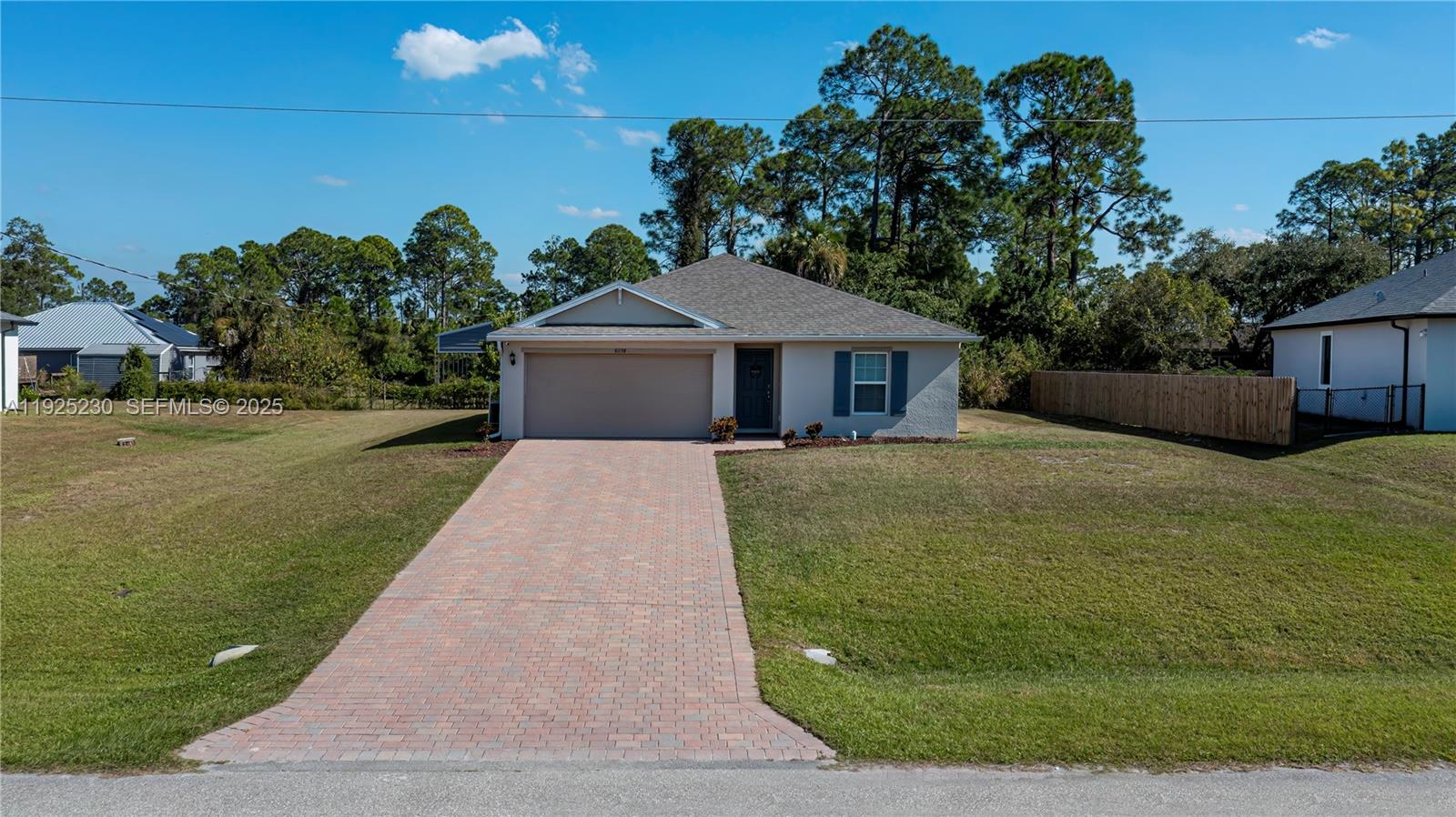 A single-story house with a paved driveway, a two-car garage, and a fenced yard — 6058 S Moss Circle, La Belle FL 33935, LA BELLE, FL