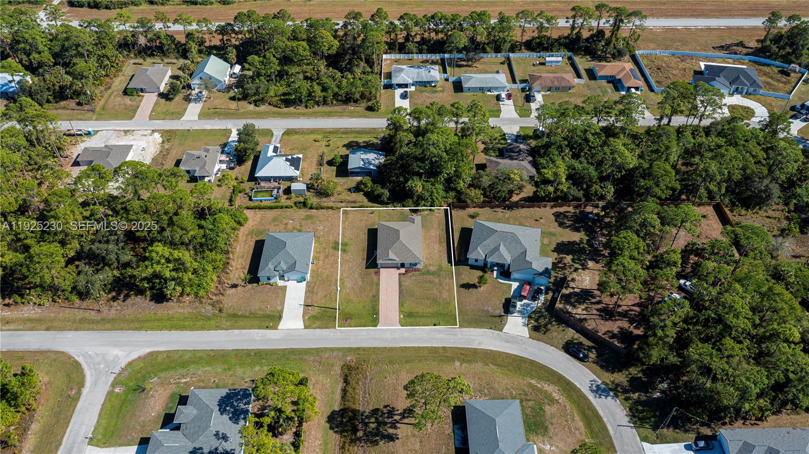 An aerial view shows a single-family house with a paved driveway in a residential neighborhood — 6058 S Moss Circle, La Belle FL 33935, LA BELLE, FL
