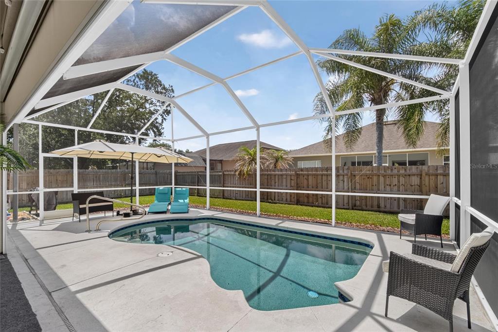 A screened-in patio features a kidney-shaped swimming pool, lounge chairs, and a wooden privacy fence — 11937 TIMBERHILL DRIVE, RIVERVIEW, FL