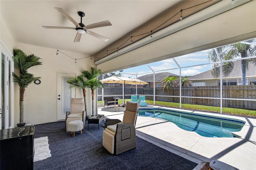 A covered patio features a ceiling fan, outdoor furniture, and a screened-in swimming pool area — 11937 TIMBERHILL DRIVE, RIVERVIEW, FL