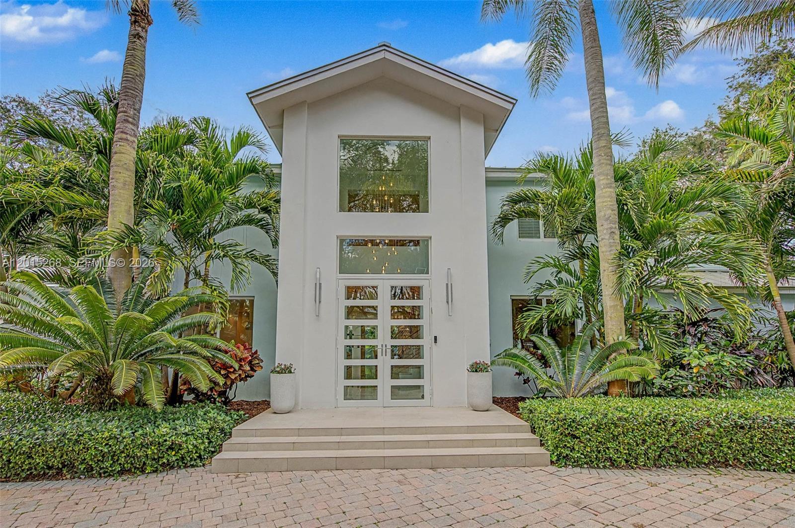 The exterior of a two-story white house features a grand entrance with glass double doors — 5790 SW 96th St, Pinecrest FL 33156, PINECREST, FL