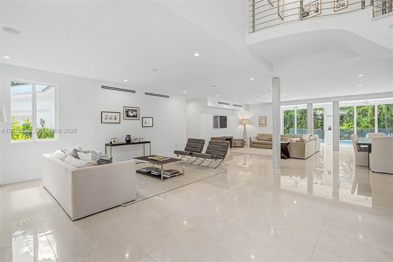 A spacious, open-concept living room features white walls, polished tile floors, and large glass doors — 5790 SW 96th St, Pinecrest FL 33156, PINECREST, FL