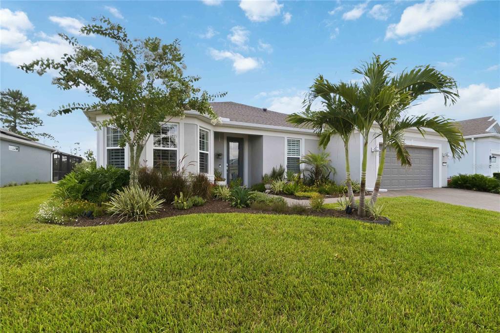 A single-story house with a gray garage, a front porch, and landscaped front yard — 2777 CHERRY BLOSSOM LOOP, ST CLOUD, FL