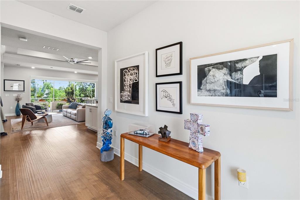 A hallway with wood floors leads to an open living area with a patio view — 2777 CHERRY BLOSSOM LOOP, ST CLOUD, FL