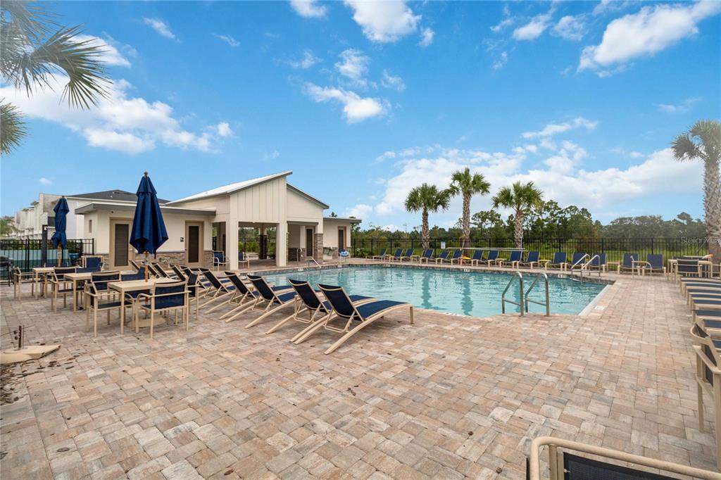 A swimming pool with lounge chairs and a clubhouse under a blue sky — 299 NINE IRON DRIVE, DAVENPORT, FL