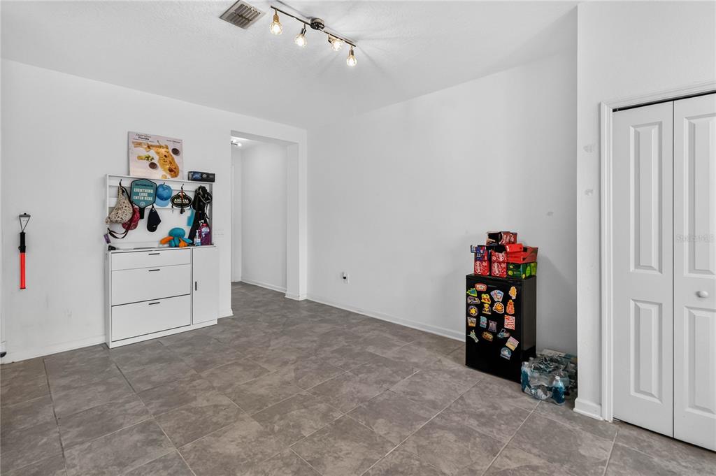A room with gray tile flooring, white walls, a storage cabinet, and a small refrigerator — 299 NINE IRON DRIVE, DAVENPORT, FL