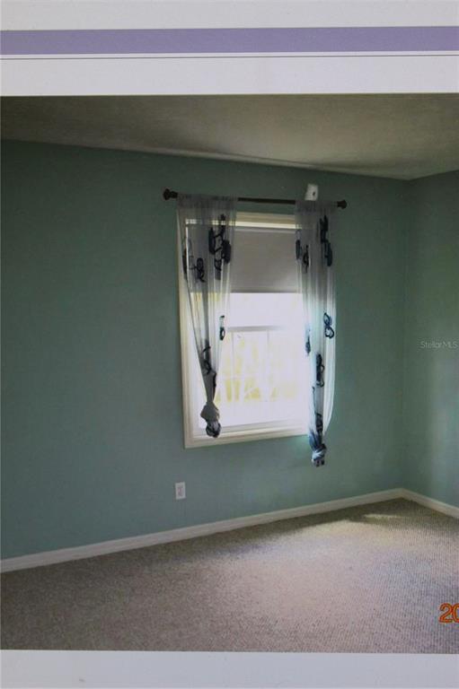 A bedroom with light blue walls, beige carpeting, and a window with patterned sheer curtains — 13735 JUNIPER BLOSSOM DRIVE, TAMPA, FL
