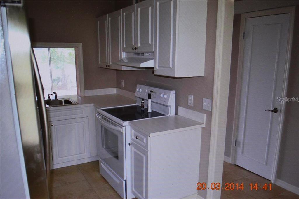 A kitchen features white cabinets, a white electric stove, and a stainless steel refrigerator — 13735 JUNIPER BLOSSOM DRIVE, TAMPA, FL