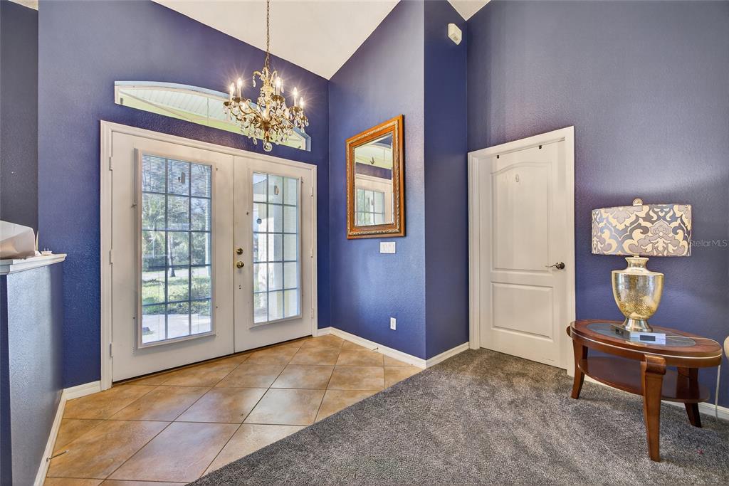 An entryway features blue walls, a chandelier, tile flooring, and a carpeted area with furniture — 7270 PARAGON ROAD, NORTH PORT, FL