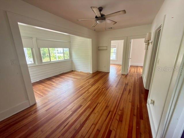 An interior view of a room with hardwood floors, a ceiling fan, and large windows — 1416 LOCUST STREET NE, ST PETERSBURG, FL