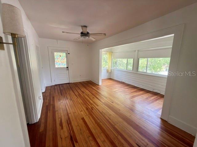 An interior view of a room with hardwood floors, a ceiling fan, and large windows — 1416 LOCUST STREET NE, ST PETERSBURG, FL