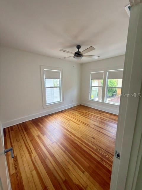 An empty bedroom features hardwood floors, white walls, a ceiling fan, and two windows — 1416 LOCUST STREET NE, ST PETERSBURG, FL