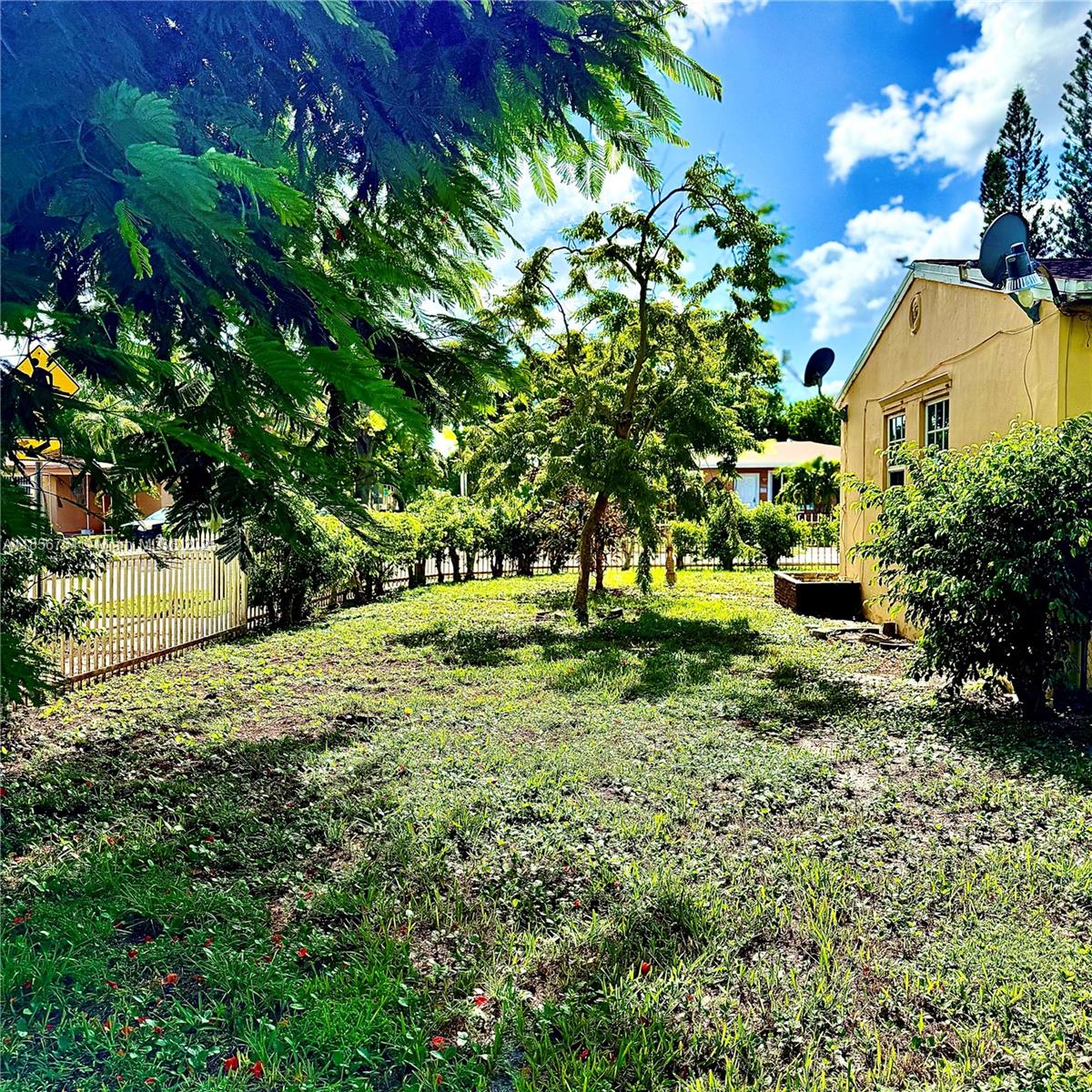 A grassy backyard with a tree, a white fence, and the side of a house — 17001 NE 6th Ct, North Miami Beach FL 33162, NORTH MIAMI BEACH, FL