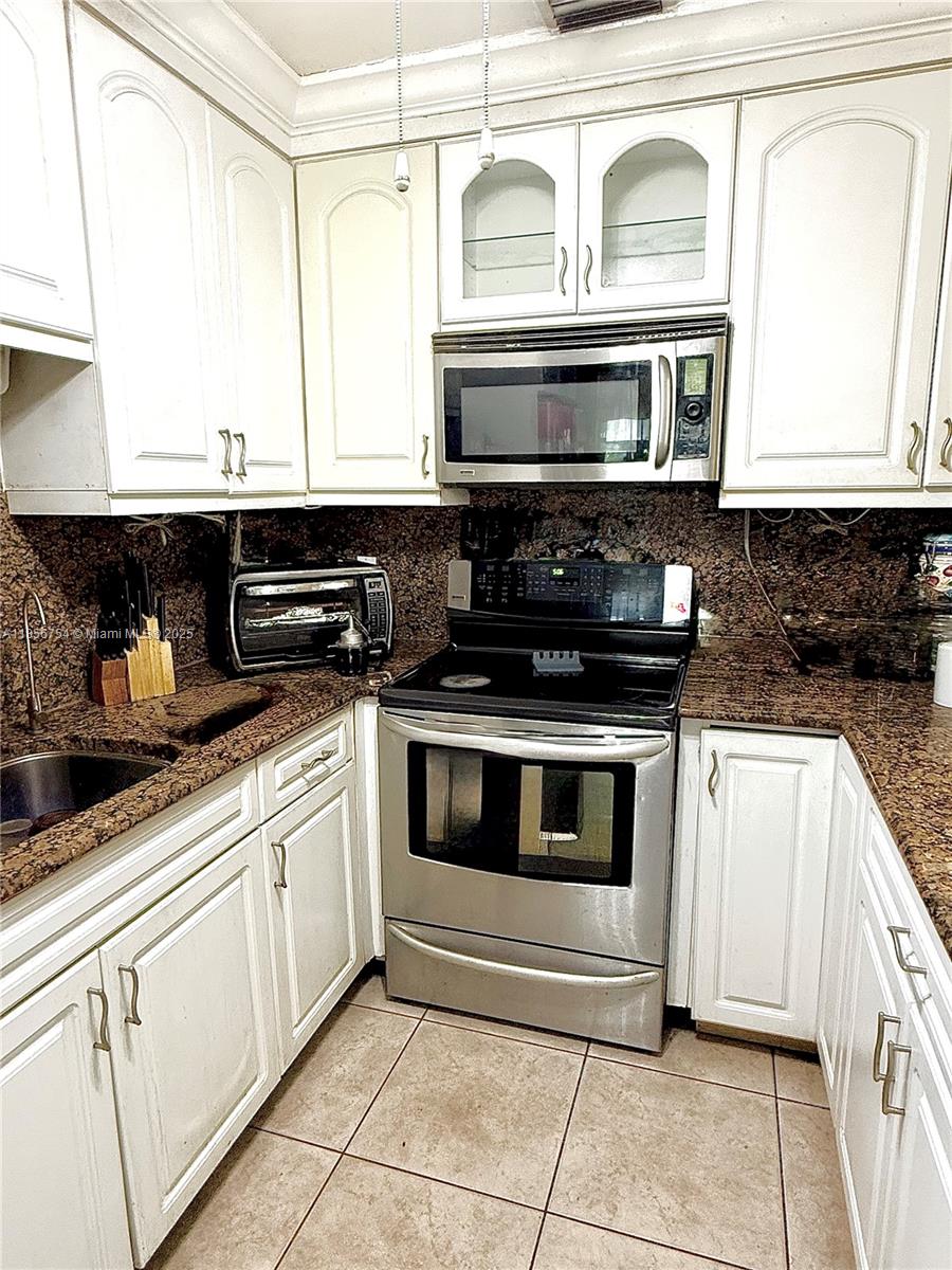 A kitchen features white cabinets, stainless steel appliances, and brown granite countertops — 17001 NE 6th Ct, North Miami Beach FL 33162, NORTH MIAMI BEACH, FL