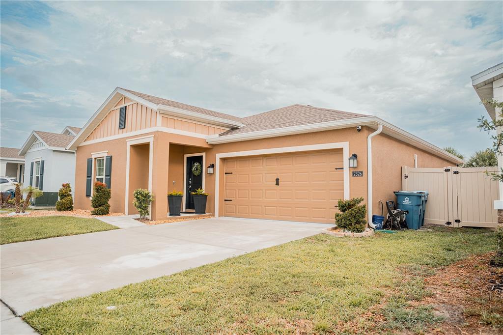 A tan single-story house with a two-car garage, a covered entryway, and a vinyl fence — 2326 BURNEY FALLS LANE, DAVENPORT, FL