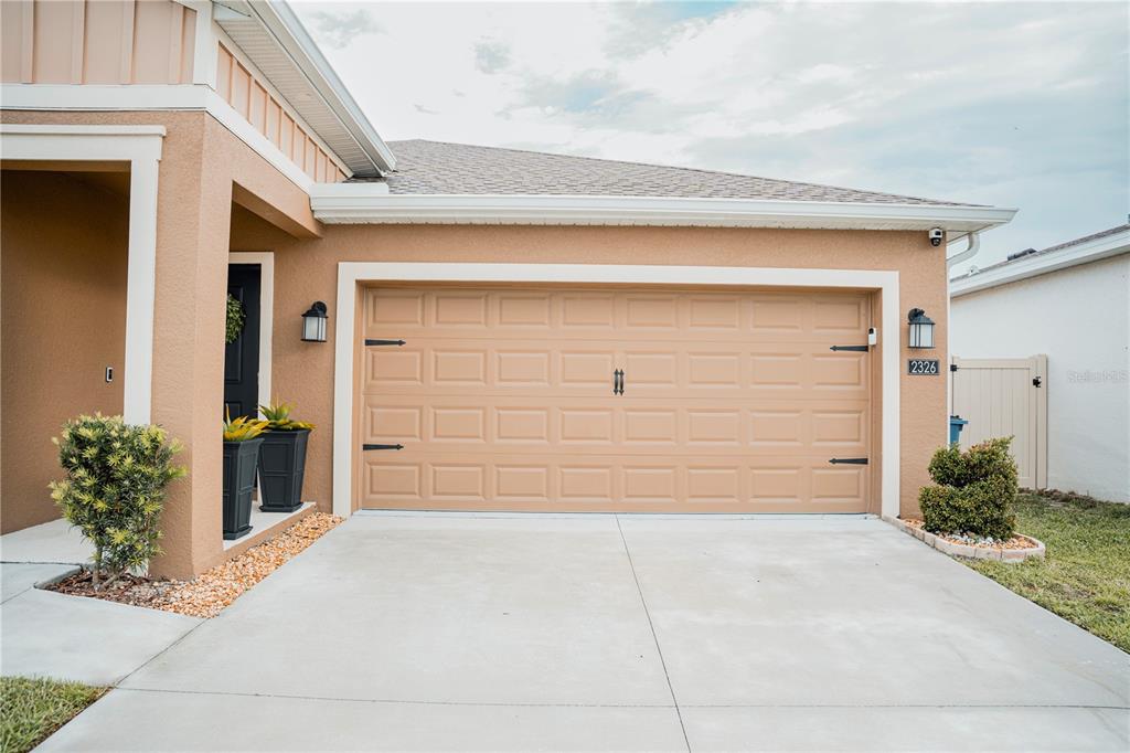 The exterior of a house features a tan stucco facade, a garage, and a driveway — 2326 BURNEY FALLS LANE, DAVENPORT, FL