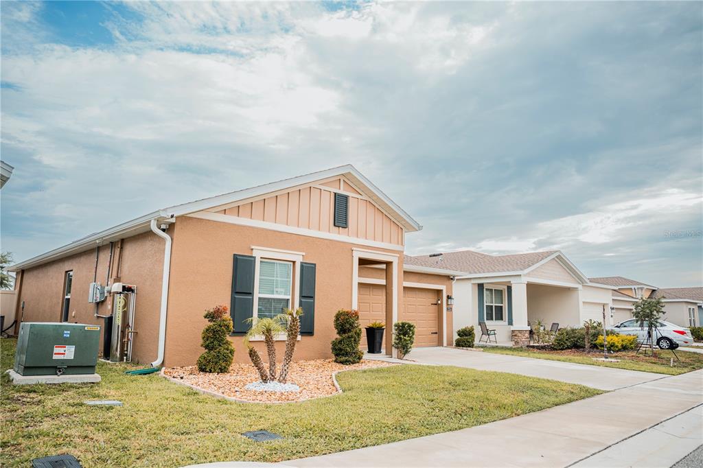 A tan single-story house with a garage, shutters, and a landscaped front yard — 2326 BURNEY FALLS LANE, DAVENPORT, FL