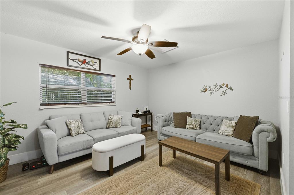 A living room features two gray sofas, a wooden coffee table, and a ceiling fan — 3017 NE 24TH COURT, OCALA, FL