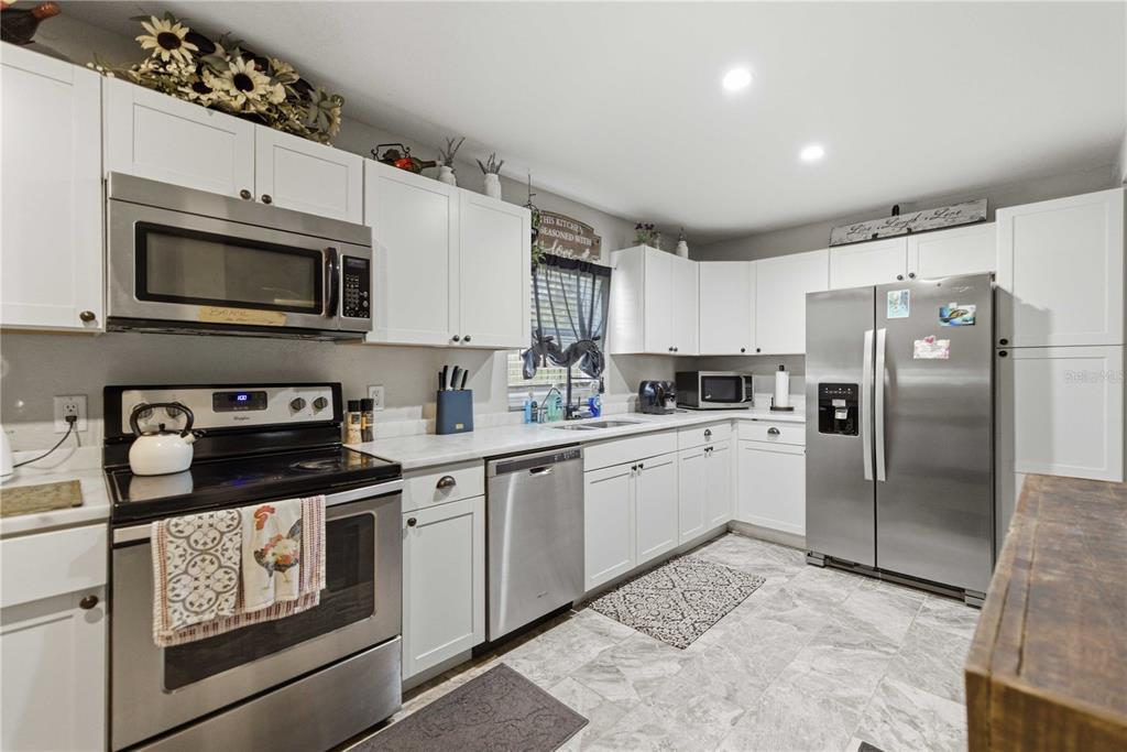A kitchen with white cabinets, stainless steel appliances, and gray tile flooring — 3017 NE 24TH COURT, OCALA, FL