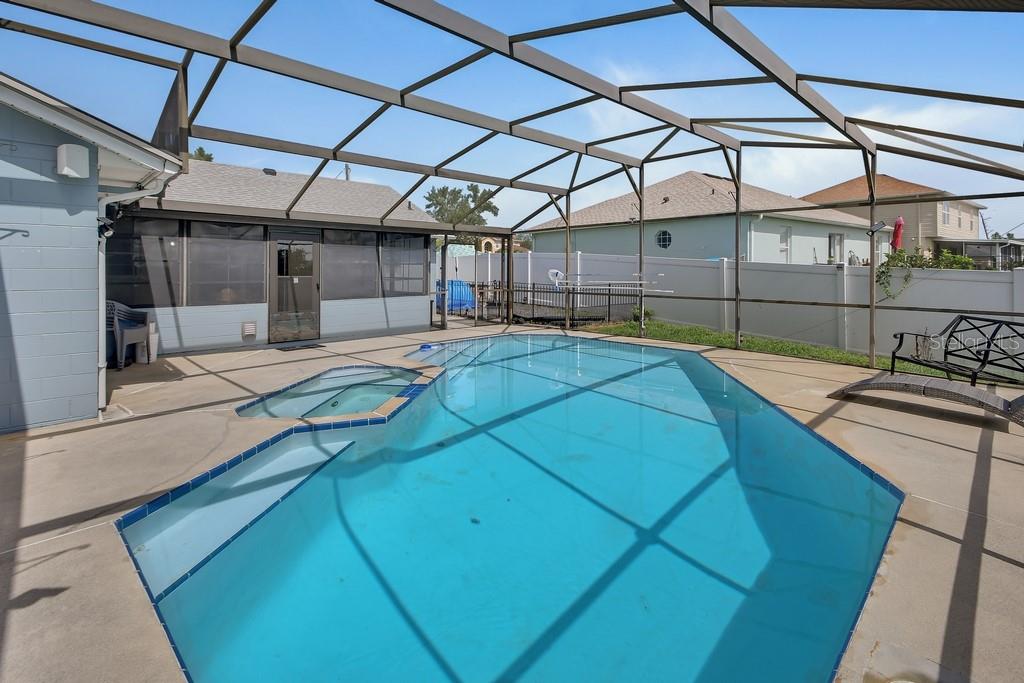 A backyard swimming pool and attached hot tub are enclosed by a screened-in lanai — 3018 BONKIRK DRIVE, DELTONA, FL