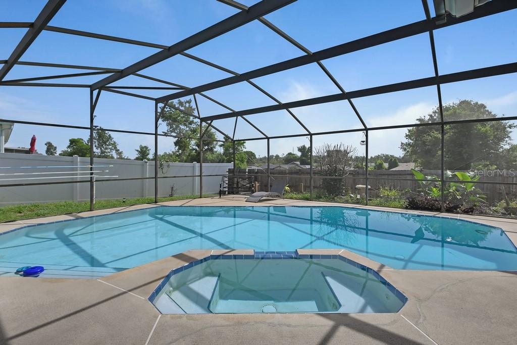 A screened-in pool and spa area with a concrete deck and a fenced backyard — 3018 BONKIRK DRIVE, DELTONA, FL