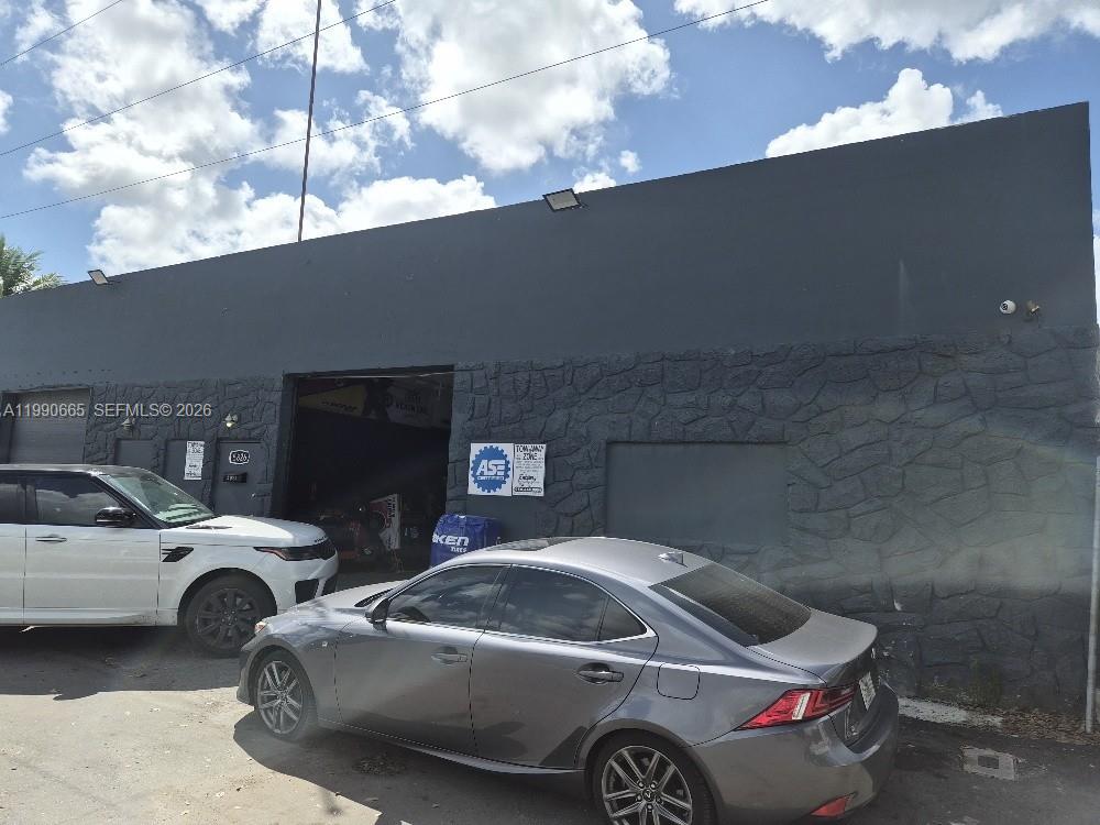 A gray commercial building with a stone-textured facade features two garage bays and parked cars — 5824 Dewey St, Hollywood FL 33023, HOLLYWOOD, FL