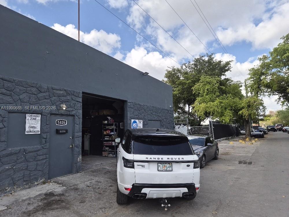 A white Range Rover is parked in front of a gray industrial building with a garage — 5824 Dewey St, Hollywood FL 33023, HOLLYWOOD, FL